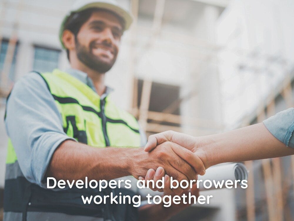 Two tradespeople shaking hands. Wearing high-visibility jacket and hard hat.